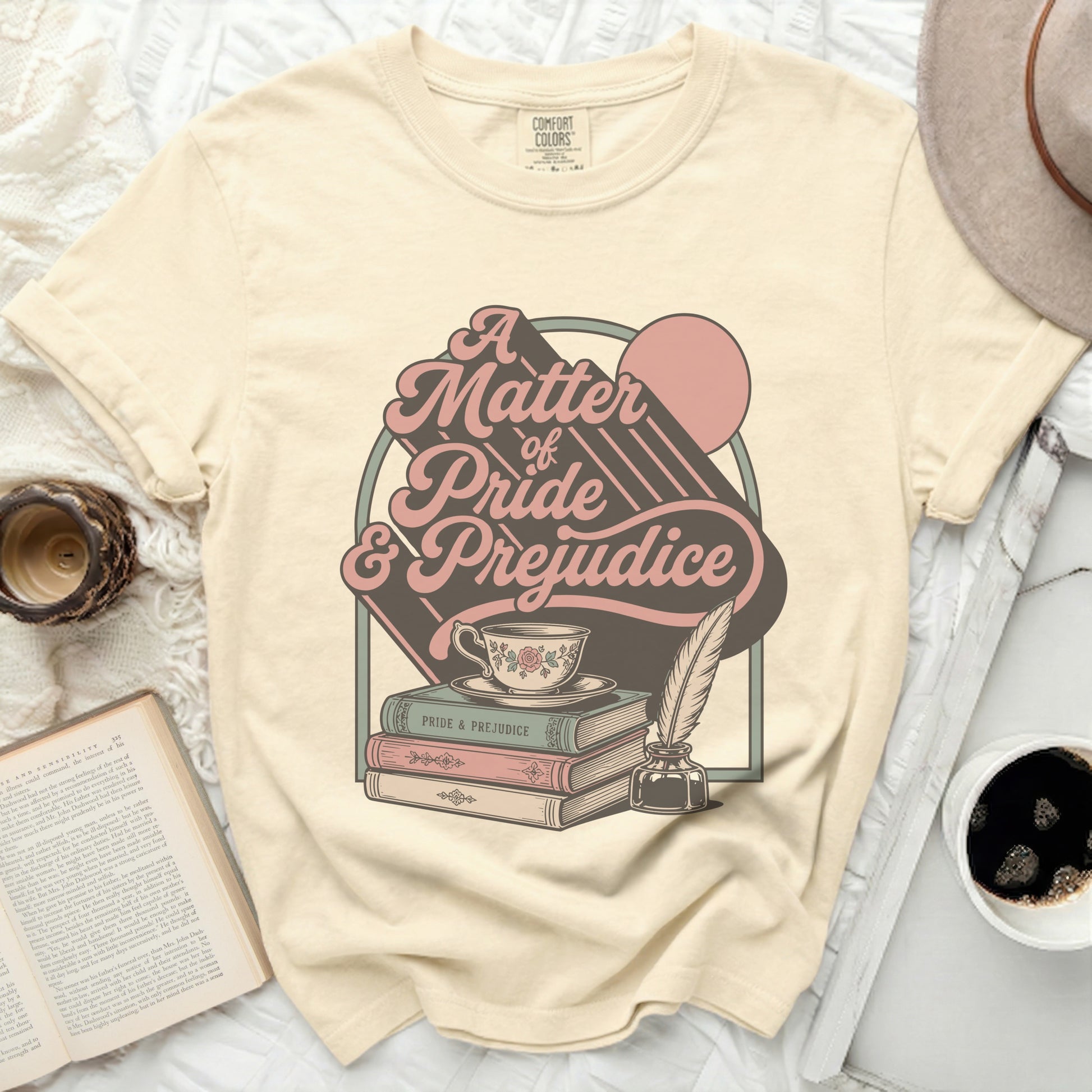 Cream t-shirt with "A Matter of Pride & Prejudice" graphic, teacup, books, and quill.