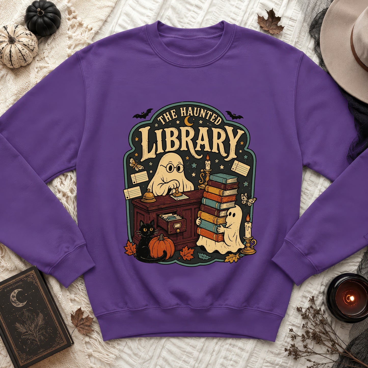 Purple sweatshirt with "The Haunted Library" graphic featuring ghosts and a black cat.