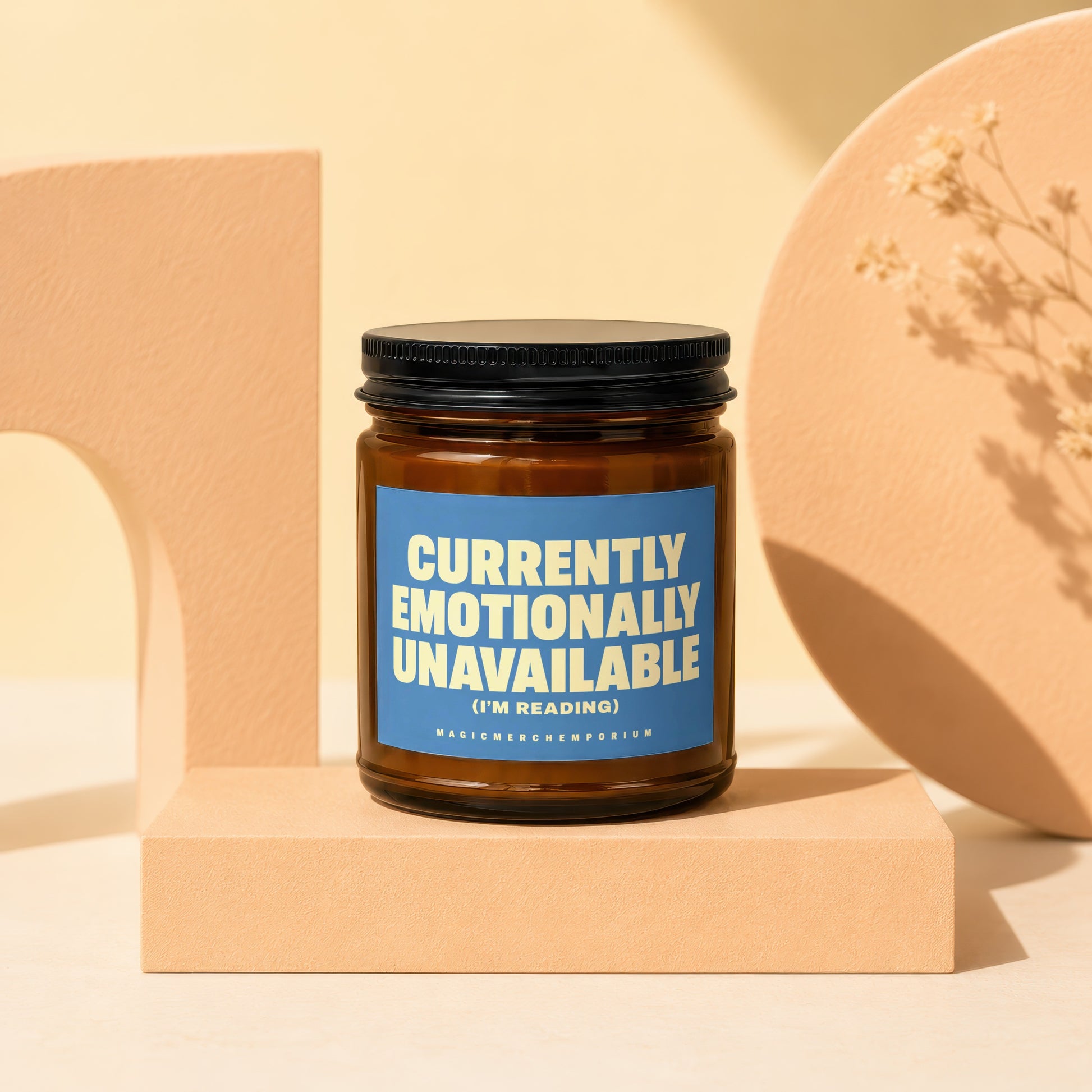 Amber jar candle with blue label reading "Currently Emotionally Unavailable (I'm Reading)".