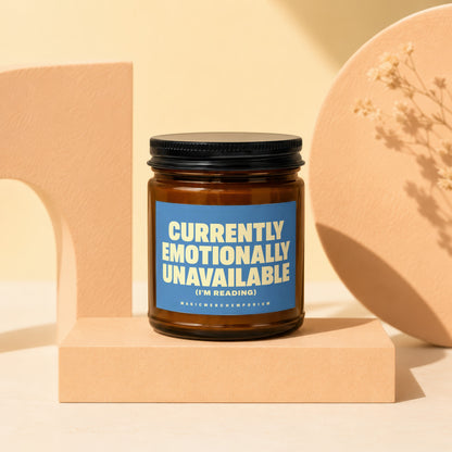 Amber jar candle with blue label reading "Currently Emotionally Unavailable (I'm Reading)".