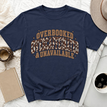 Navy t-shirt with "Overbooked & Unavailable" text in brown and cow print.