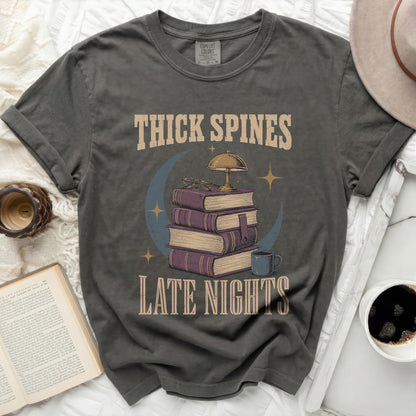 Graphic tee with "Thick Spines Late Nights" and stack of books design.