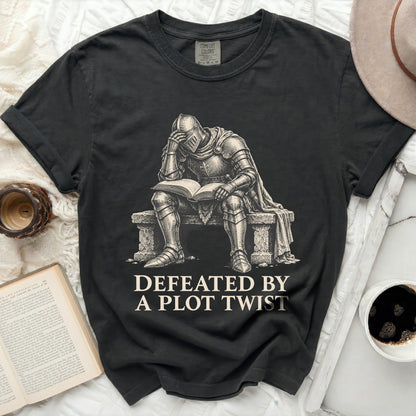 T-shirt with knight reading a book, text reads "Defeated by a plot twist."