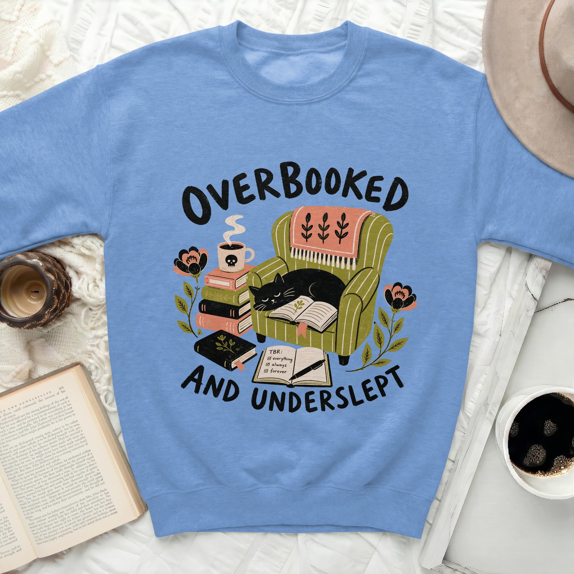 Sweatshirt with "Overbooked and Underslept" design featuring a cat in a chair.