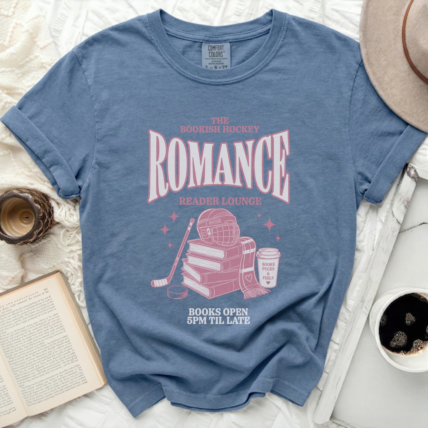 Blue t-shirt with "Bookish Hockey Reader Lounge" text, hockey gear, and books.