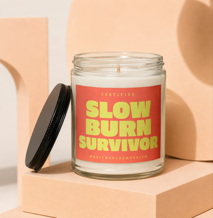 Glass jar candle with red label that says "CERTIFIED SLOW BURN SURVIVOR"