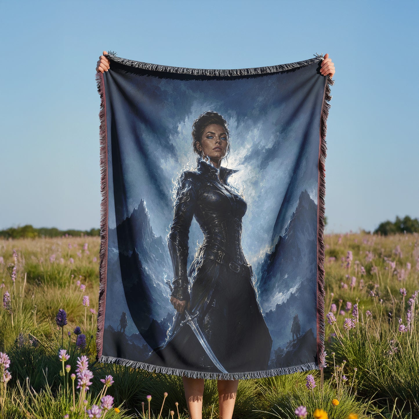 A person is holding a large blanket with a painting of a woman on it, standing in a field with purple flowers.