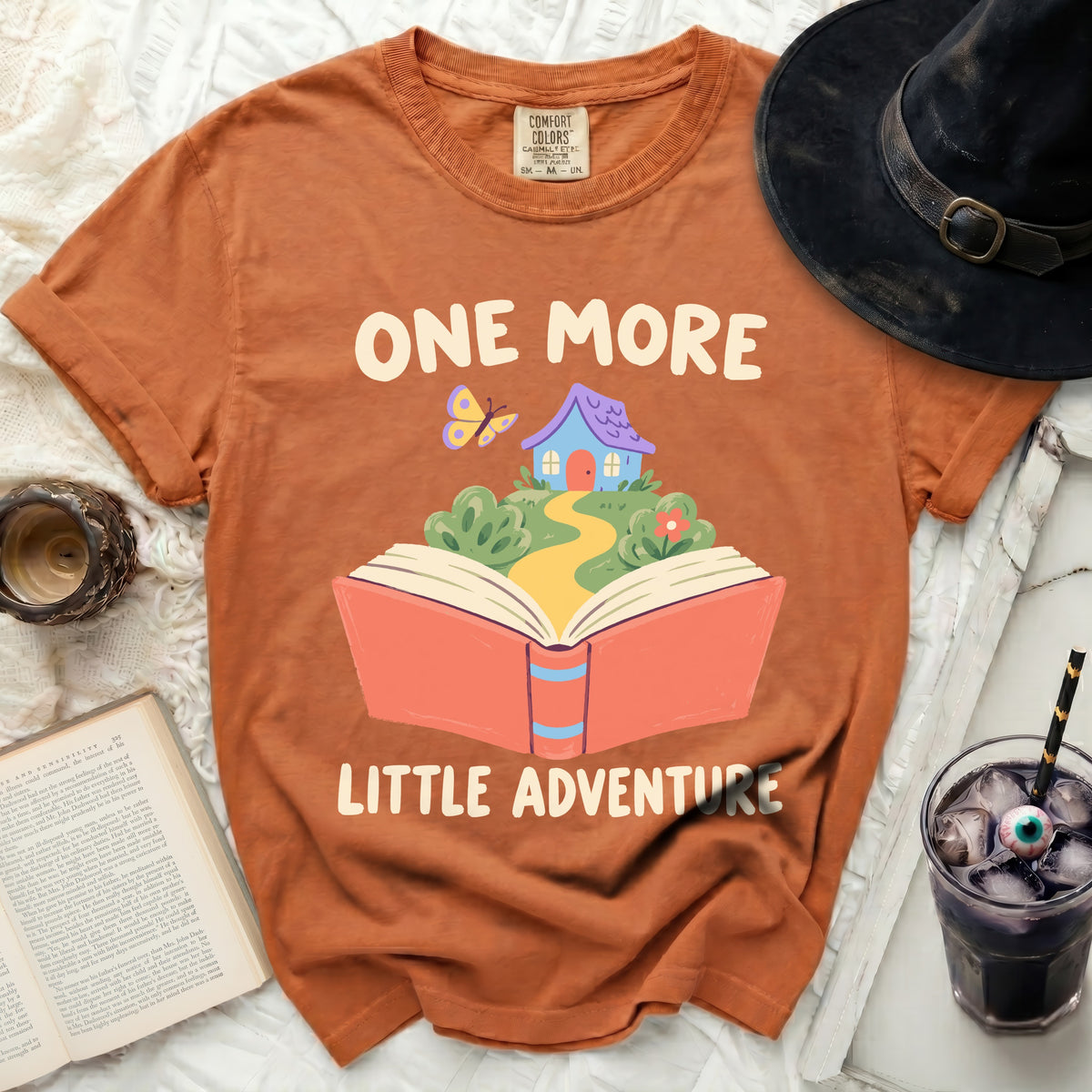 Orange t-shirt with "ONE MORE LITTLE ADVENTURE" text and graphic.