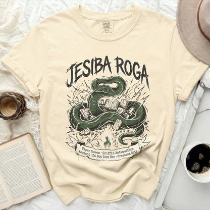 Cream t-shirt with green snake and books graphic, "Jesiba Roga" text.