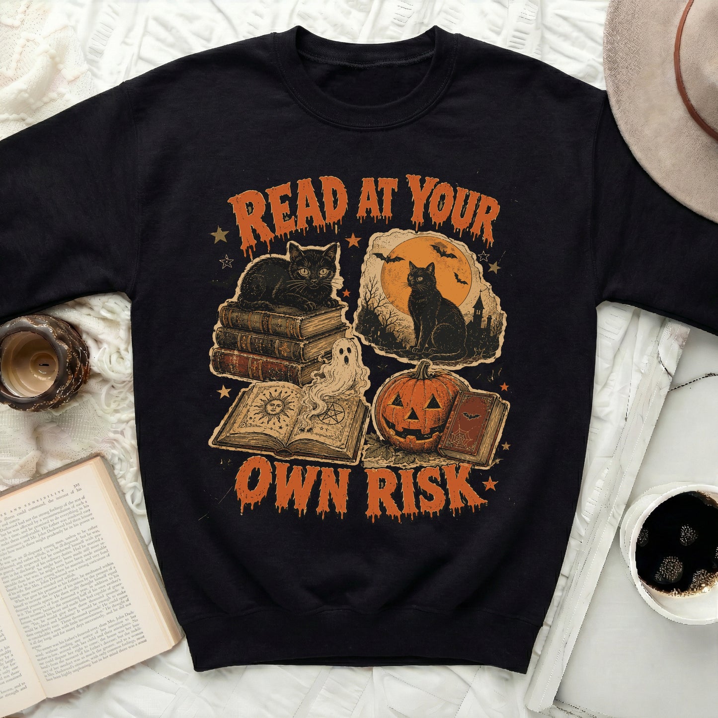 Black sweatshirt with Halloween graphic of cats, books, pumpkin, bats, and text.