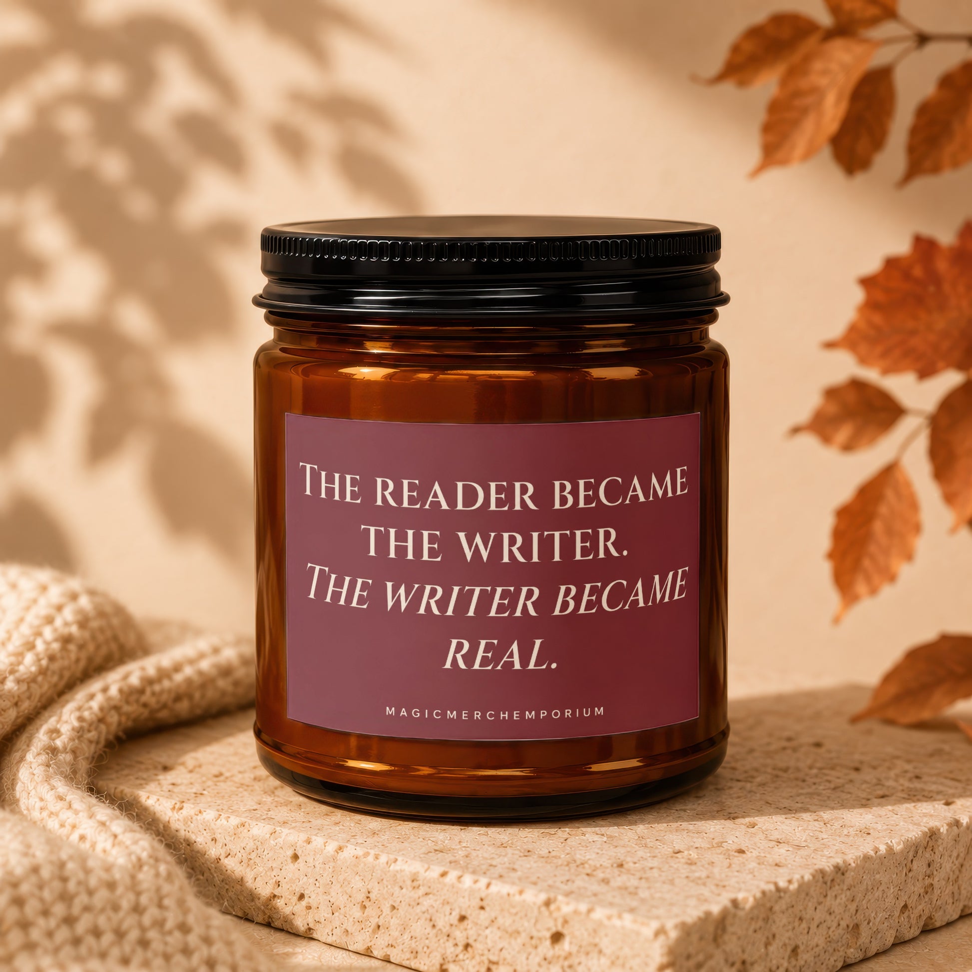 Amber candle with black lid featuring text "The reader became the writer. The writer became real."