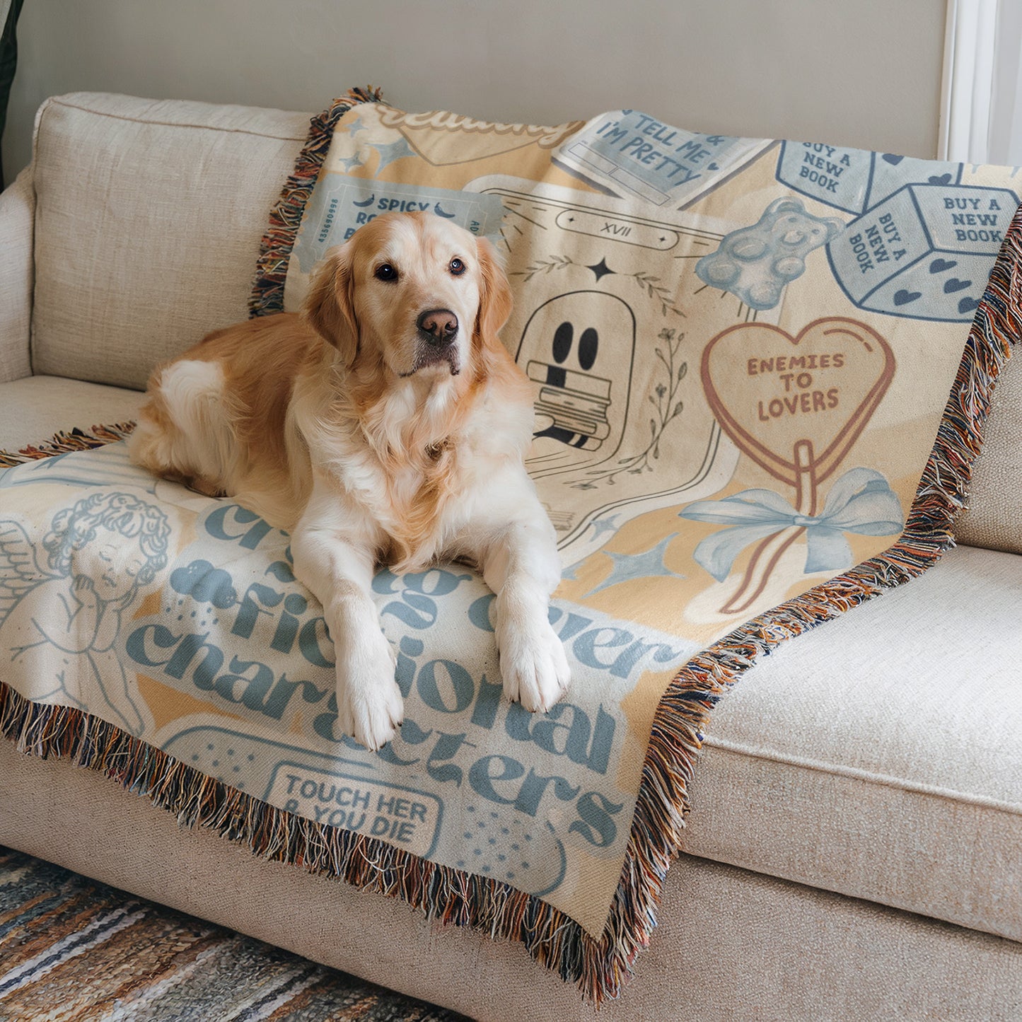 A golden retriever dog is lying on a couch with a colorful blanket featuring various text and illustrations.