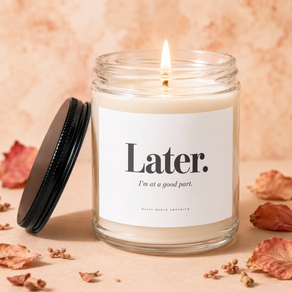 Glass candle with lit wick, black lid, and label reading "Later. I'm at a good part."