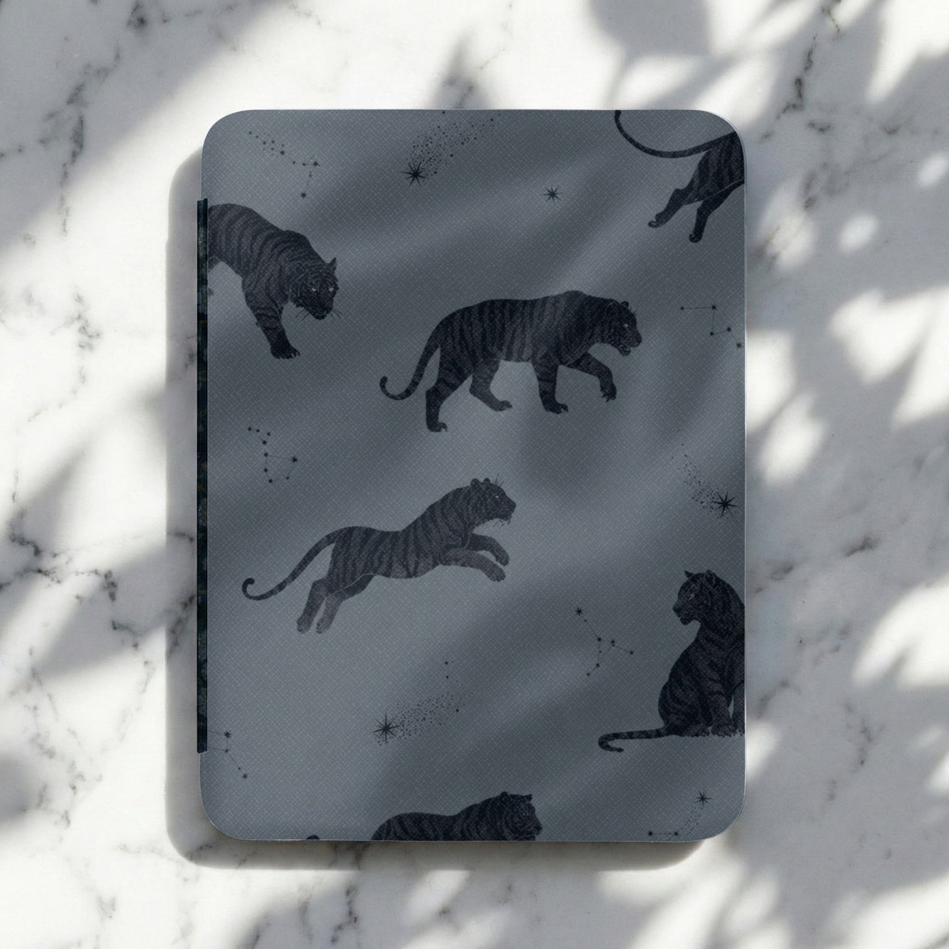 Dark gray cover with a repeating pattern of black tigers and constellations.