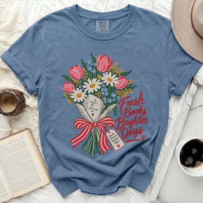Blue t-shirt with a floral bouquet and text reading "Fresh Books Brighter Days."