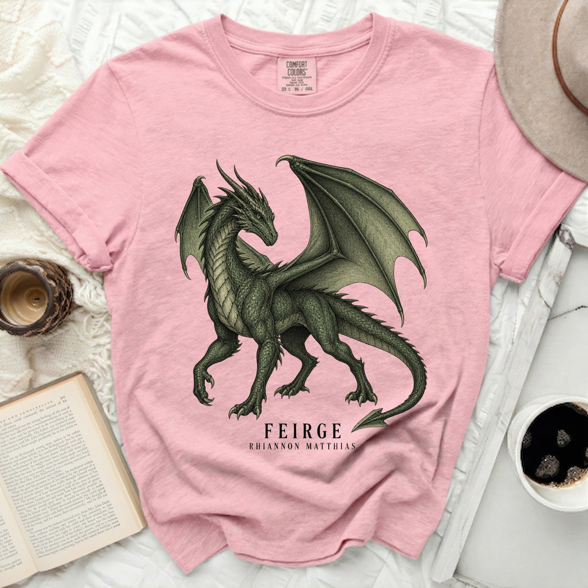 Pink t-shirt with a green dragon illustration and text "FEIRGE RHIANNON MATTHIAS".