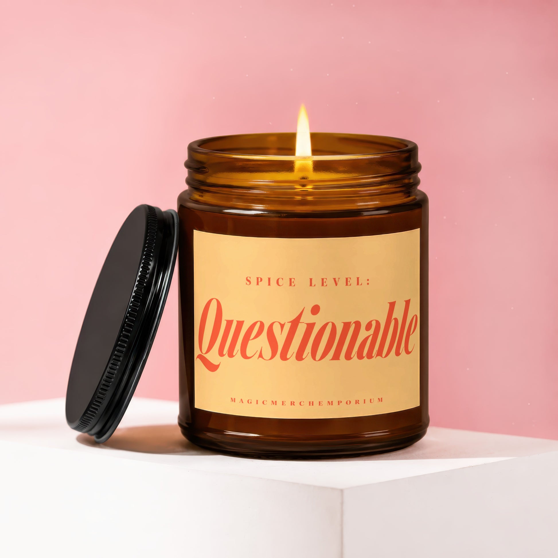 Amber candle with lit wick, lid beside it, reads "Spice Level: Questionable".