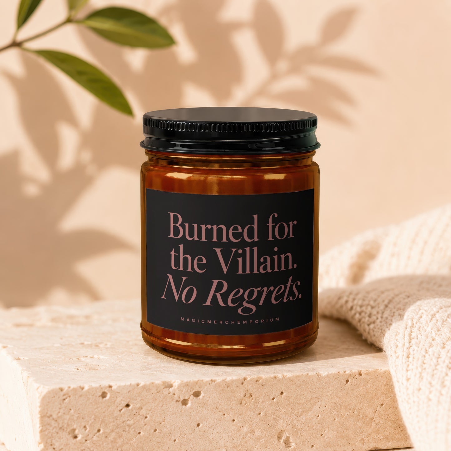 Candle with black label reading "Burned for the Villain. No Regrets." MagicMerchEmporium.