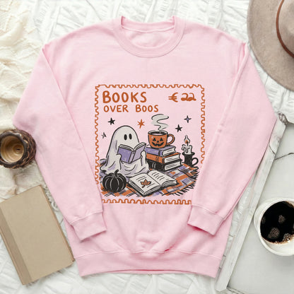 Pink sweatshirt with "Books Over Boos" and a ghost reading near a pumpkin coffee mug.