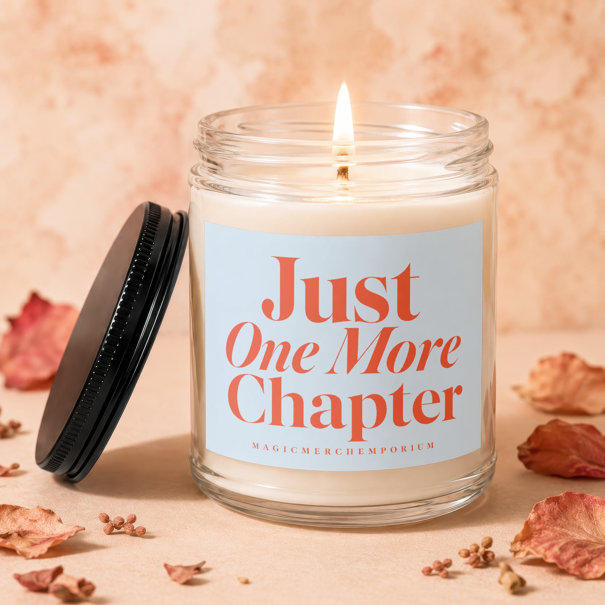 Glass candle with burning wick, lid beside it, and "Just One More Chapter" text.