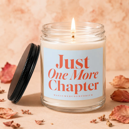 Glass candle with burning wick, lid beside it, and "Just One More Chapter" text.
