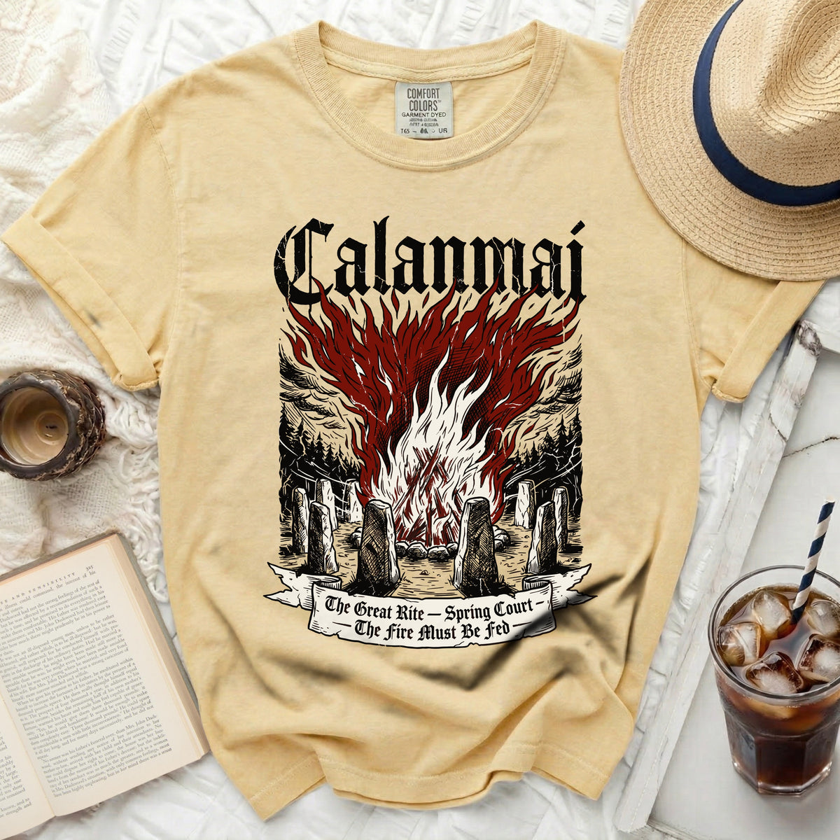 Yellow t-shirt with a graphic of "Calanmai" over a bonfire and stone circle.