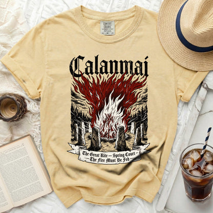 Yellow t-shirt with a graphic of "Calanmai" over a bonfire and stone circle.