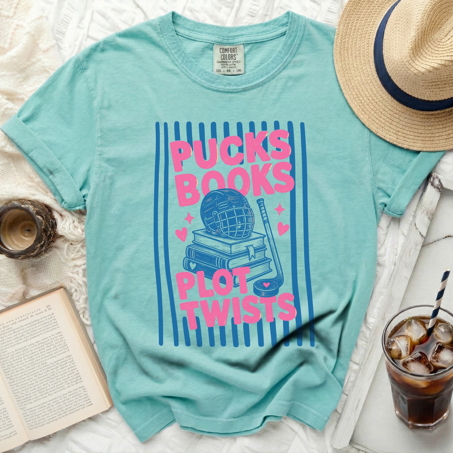 Teal t-shirt with pink stripes and "Pucks Books Plot Twists" graphic.