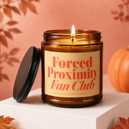 Amber jar candle with lit flame, label reads "Forced Proximity Fan Club".