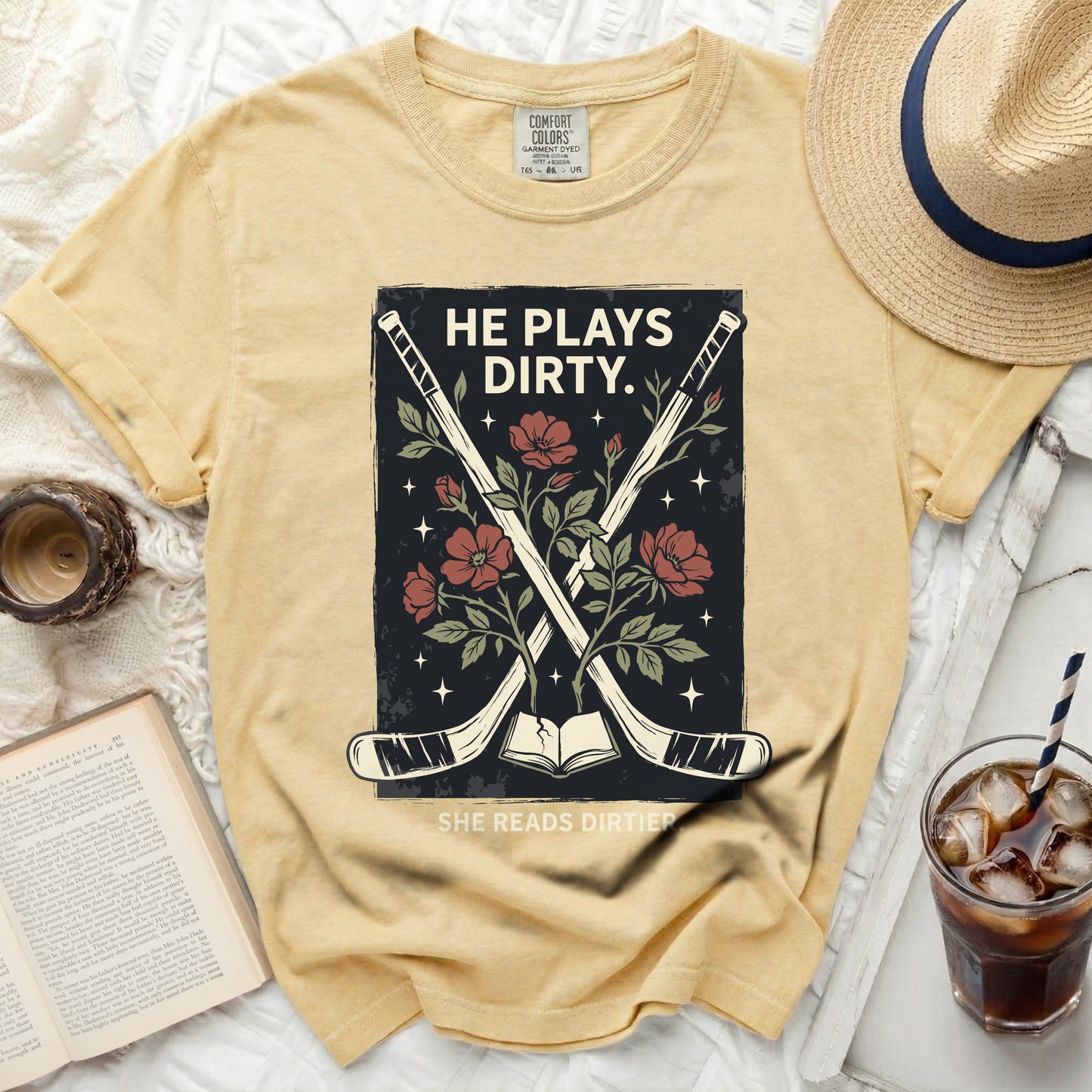 Yellow t-shirt with hockey sticks, flowers, and text "HE PLAYS DIRTY. SHE READS DIRTIER."