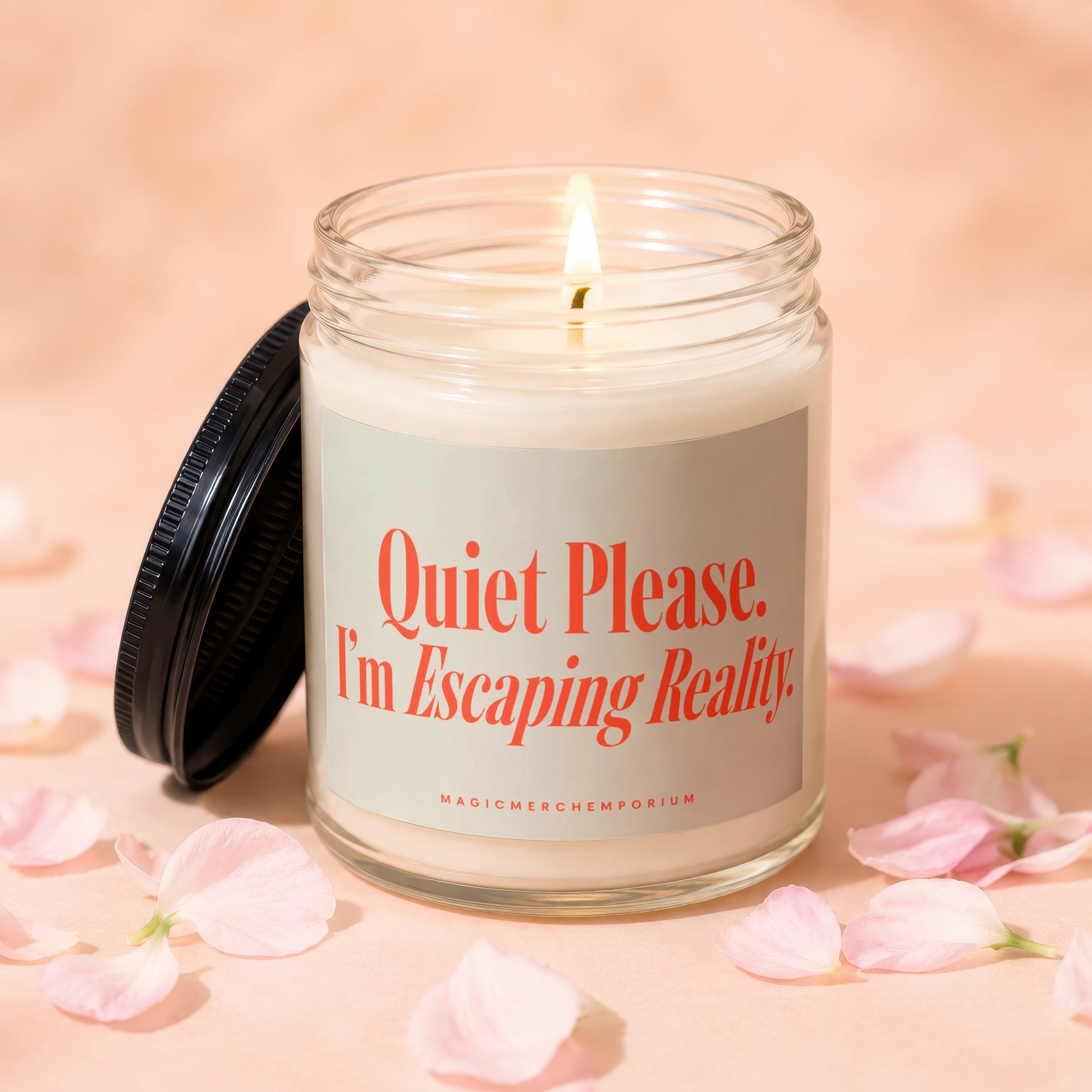 Jar candle with lit wick and black lid. Label says "Quiet Please. I'm Escaping Reality."
