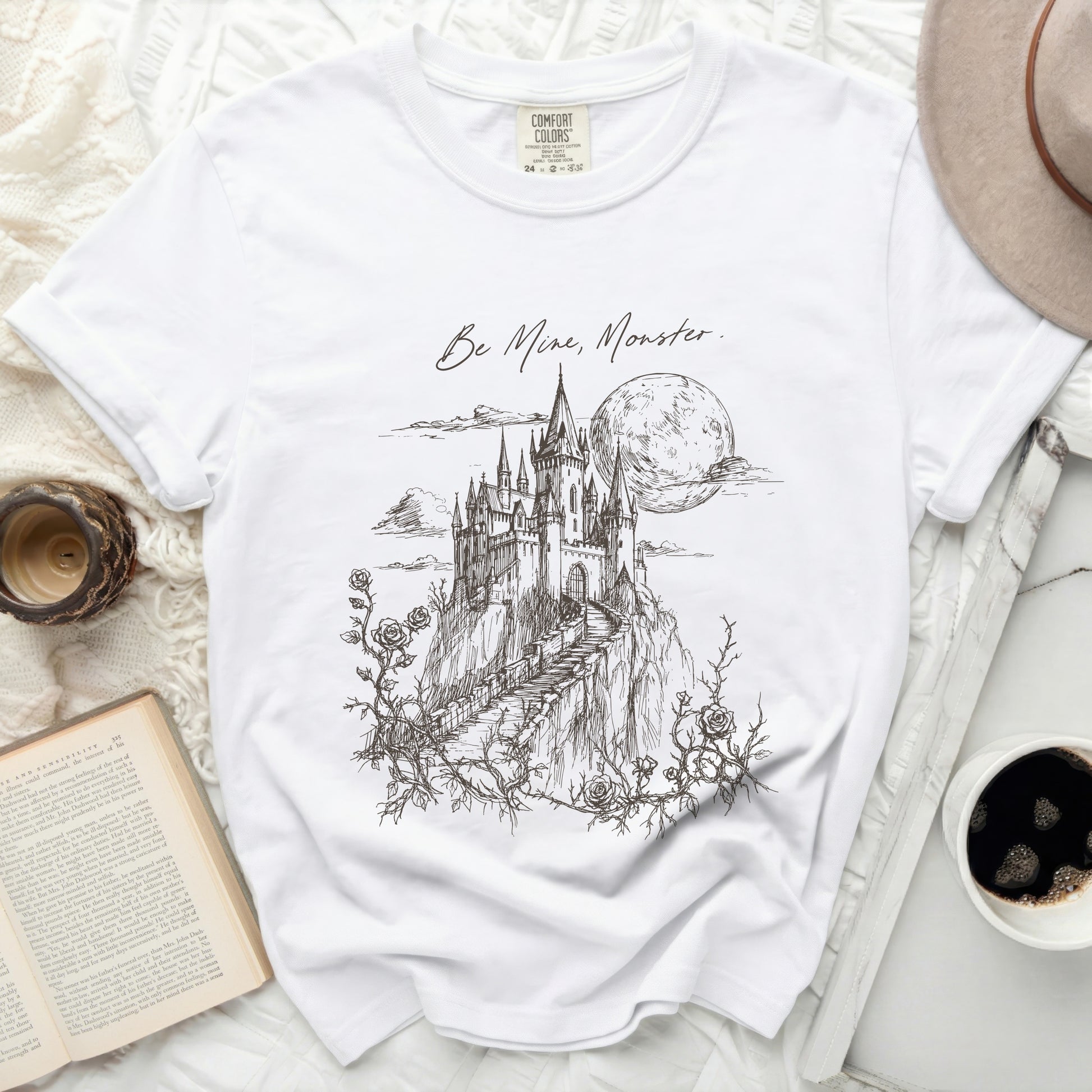 White t-shirt with "Be Mine, Monster." text and castle illustration.