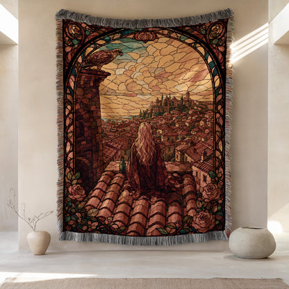 a large tapestry hanging on a wall, depicting a woman sitting on a rooftop with a cityscape in the background. The tapestry is framed with a decorative border and has a floral pattern. There are two small vases placed on either side of the tapestry, and the overall scene has a warm and inviting atmosphere.