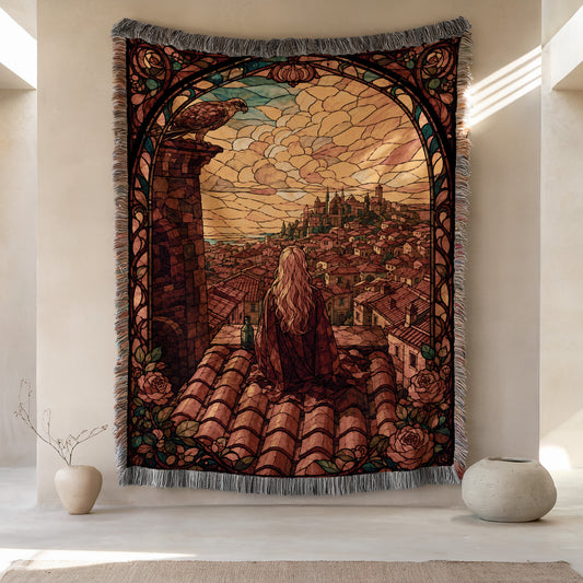 a large tapestry hanging on a wall, depicting a woman sitting on a rooftop with a cityscape in the background. The tapestry is framed with a decorative border and has a floral pattern. There are two small vases placed on either side of the tapestry, and the overall scene has a warm and inviting atmosphere.