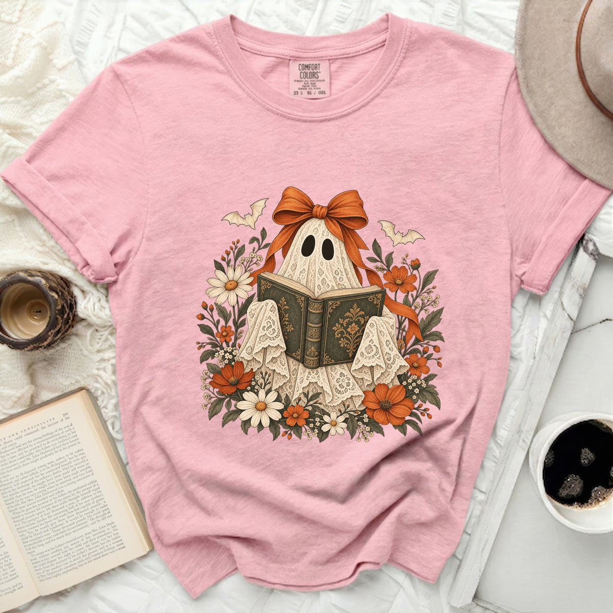Pink t-shirt with a ghost reading a book design surrounded by flowers.