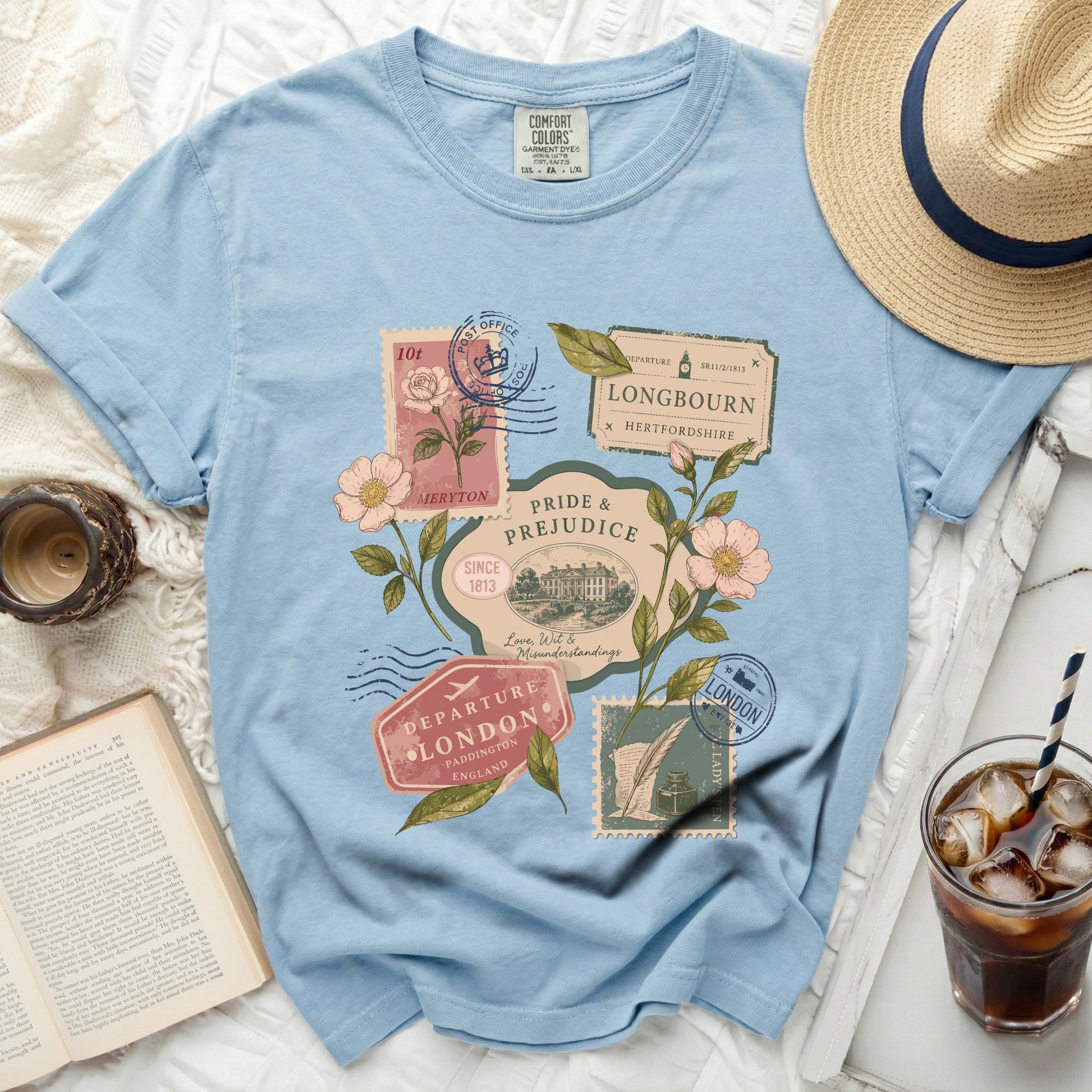 Light blue t-shirt with vintage postage stamps and flowers graphic.