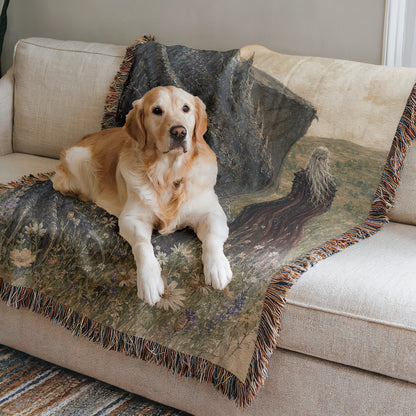 A golden retriever dog is lying on a couch with a colorful blanket featuring a landscape design.