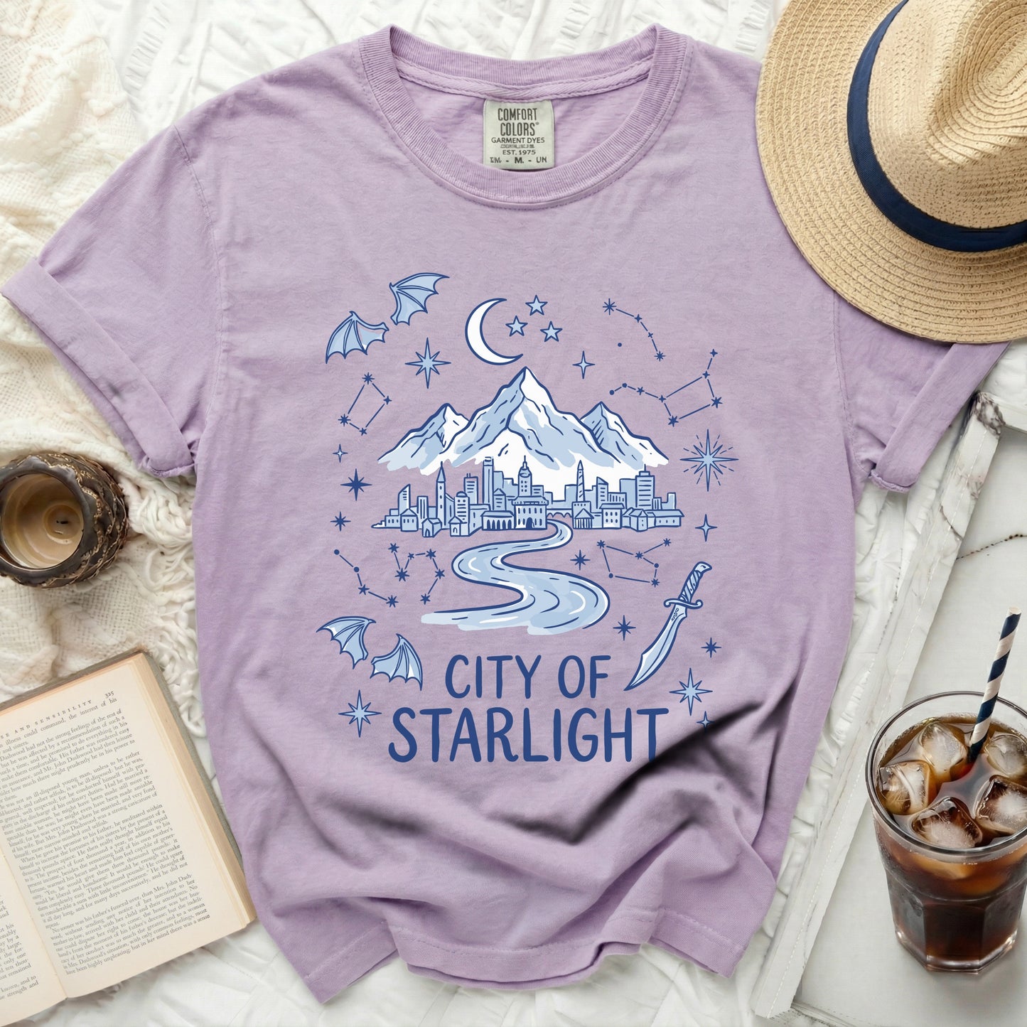 Purple t-shirt with "City of Starlight" text, cityscape, mountains, moon, stars, and bats.
