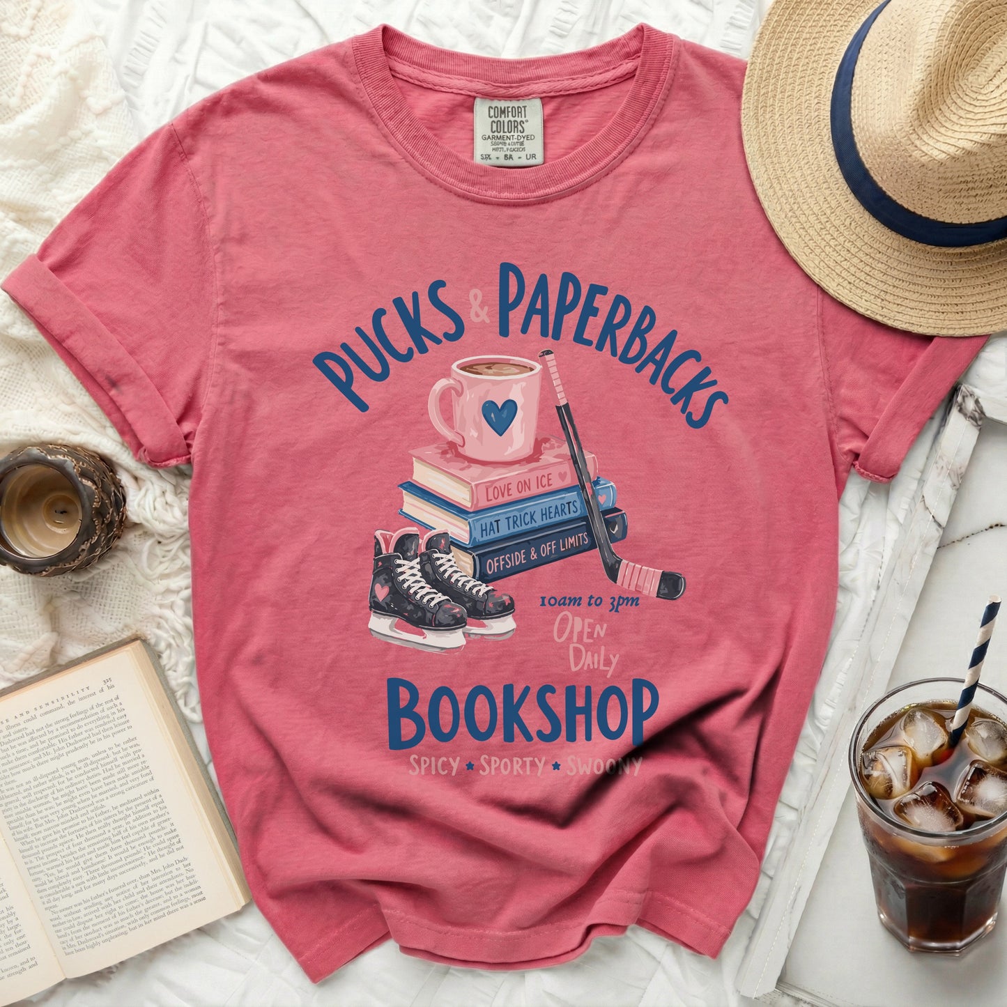 Pink t-shirt with "Pucks & Paperbacks" bookshop graphic.