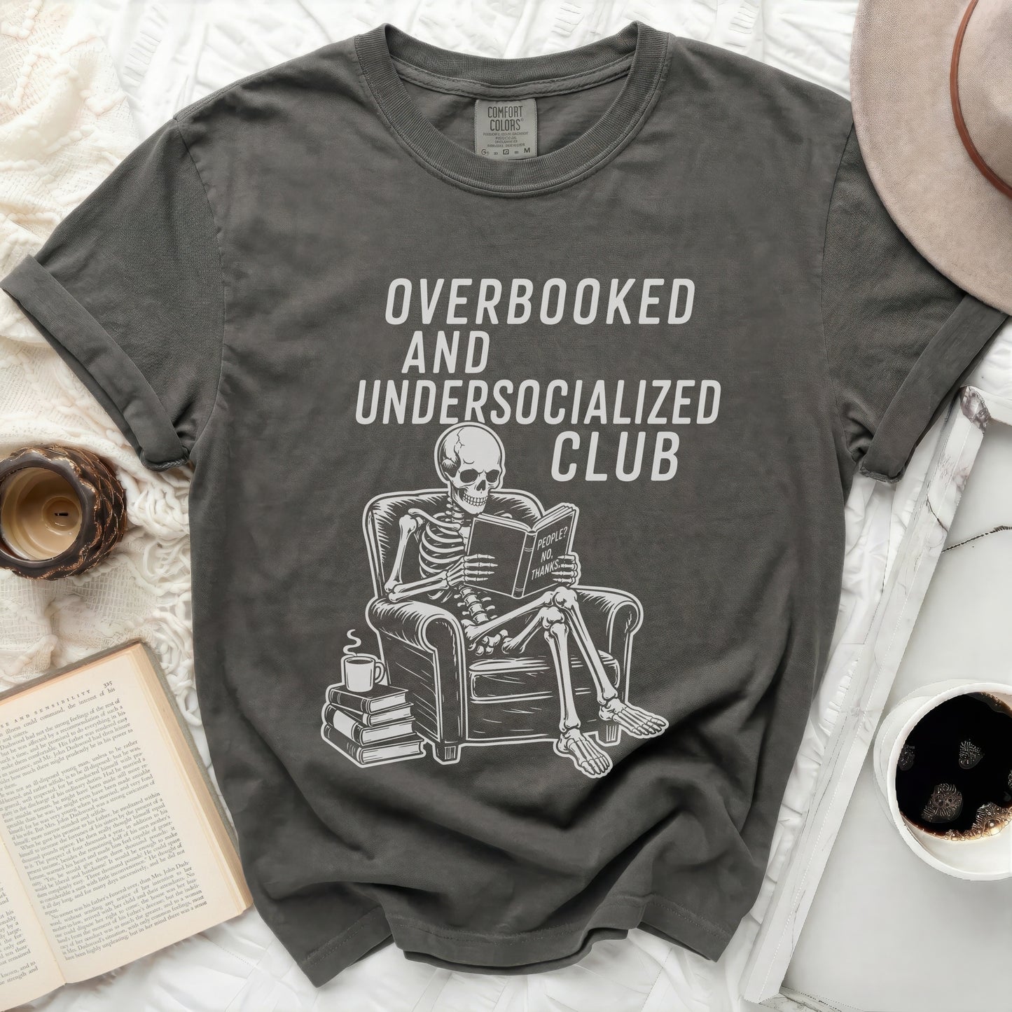 Overbooked and Undersocialized Club t-shirt with skeleton reading book.