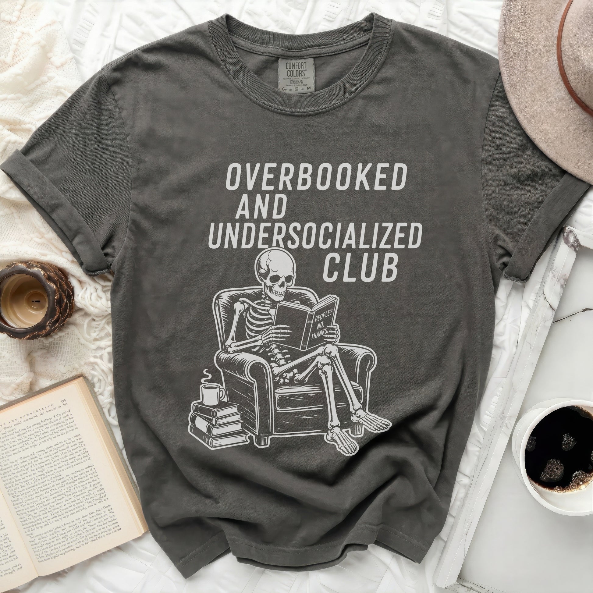 Overbooked and Undersocialized Club t-shirt with skeleton reading book.