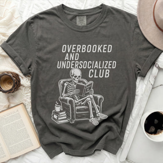 Overbooked and Undersocialized Club t-shirt with skeleton reading book.