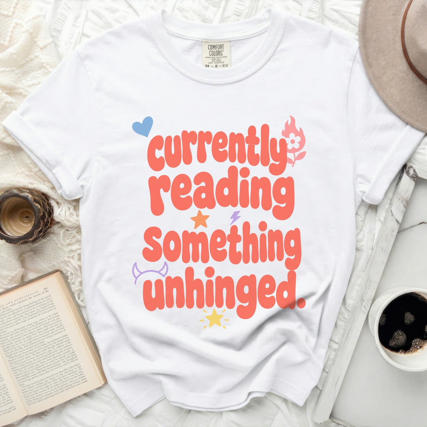White t-shirt with orange text "currently reading something unhinged"