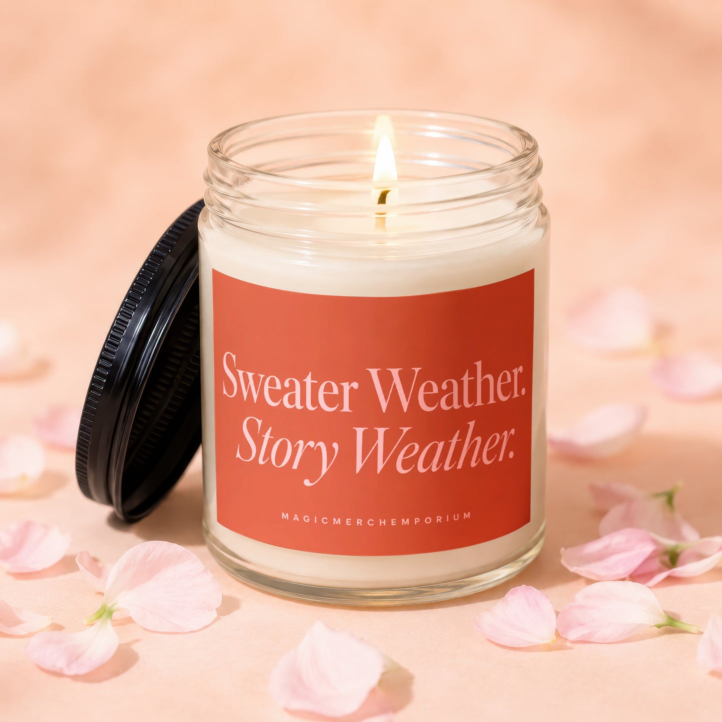 Glass candle with lit wick and orange label reading "Sweater Weather. Story Weather."