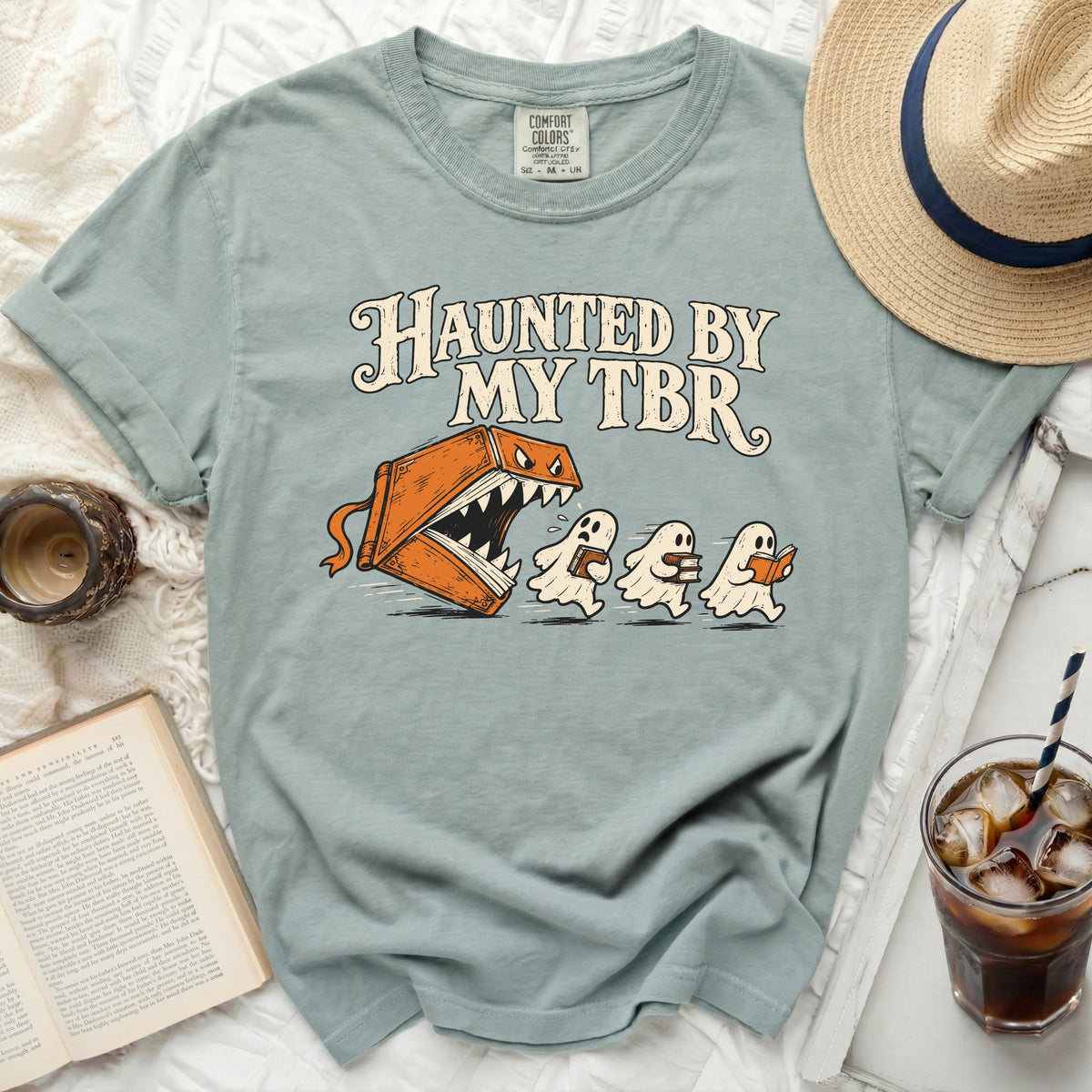 T-shirt with "Haunted by My TBR" text and illustration of a monster book chasing ghosts.