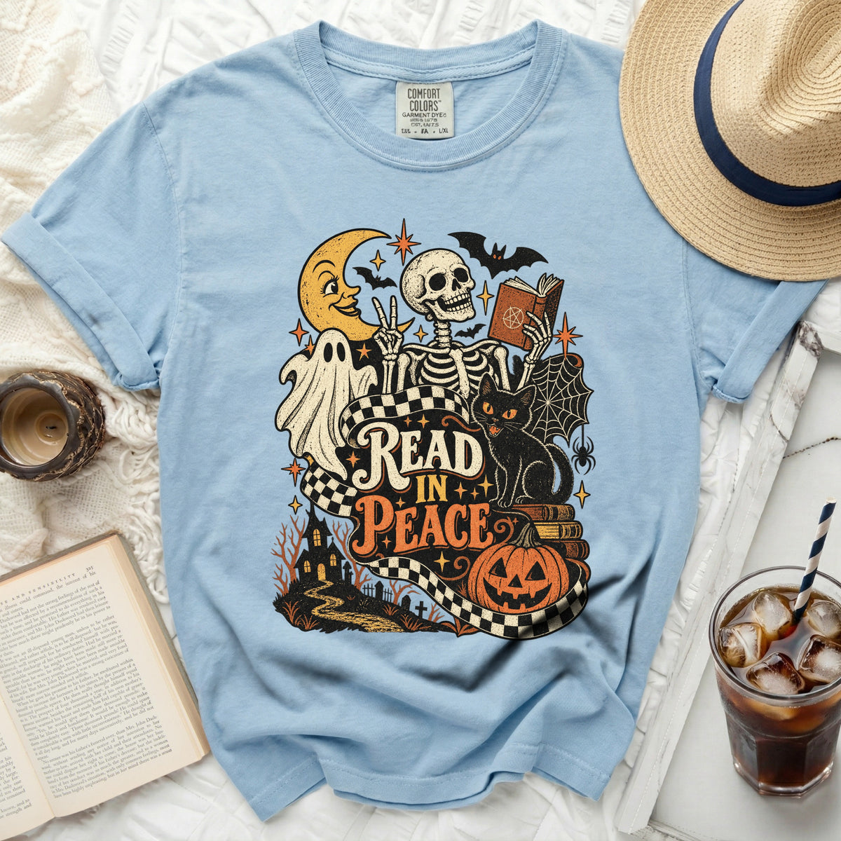 Light blue t-shirt with skeleton, ghost, cat, and Halloween graphics reading "Read In Peace."