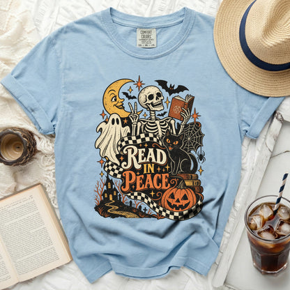 Light blue t-shirt with skeleton, ghost, cat, and Halloween graphics reading "Read In Peace."
