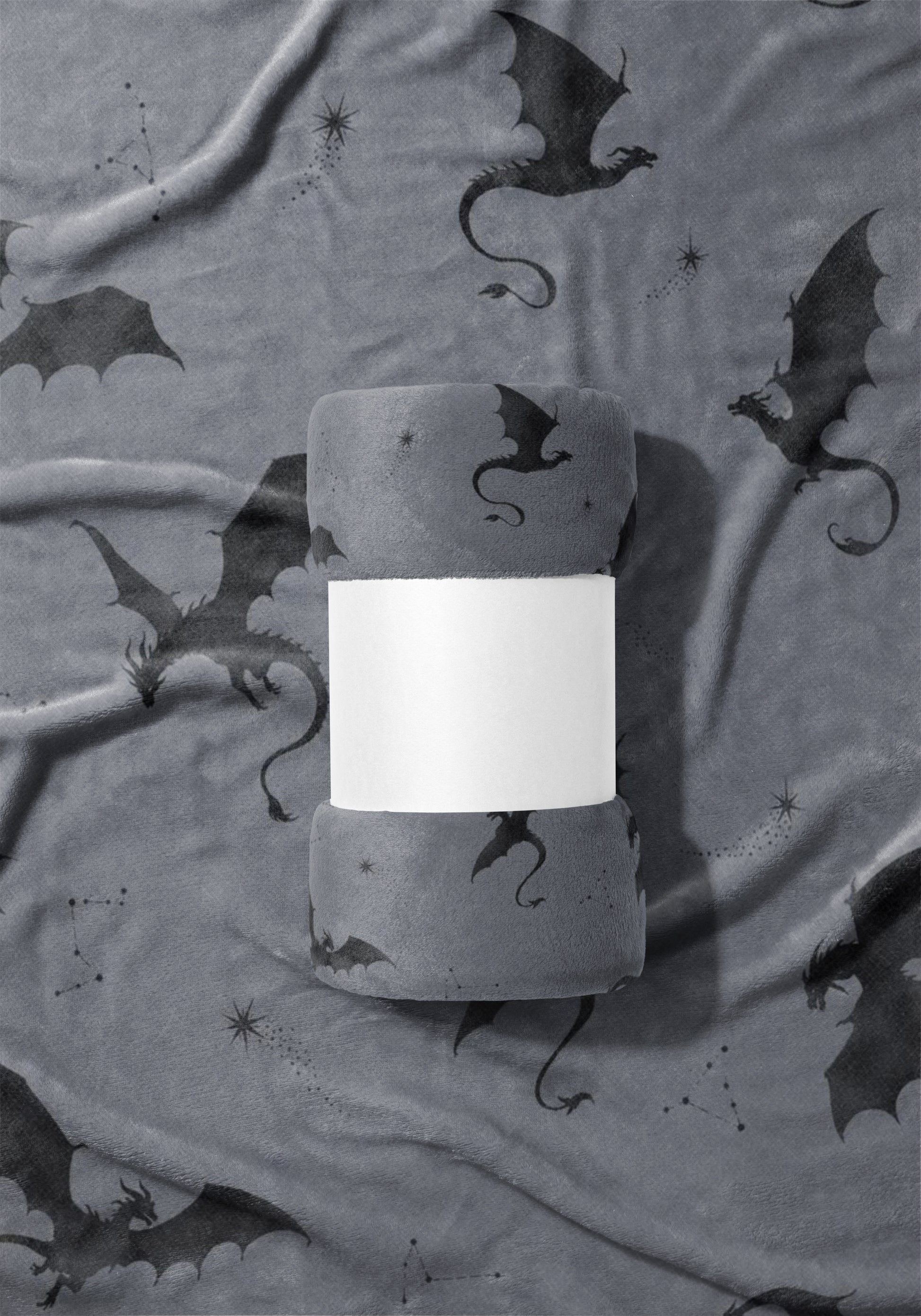 Rolled grey plush blanket featuring a dark grey dragon constellation print and a white band.