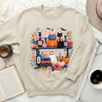 Cream sweatshirt with Halloween graphic of black cat, pumpkins, ghost, and potions.