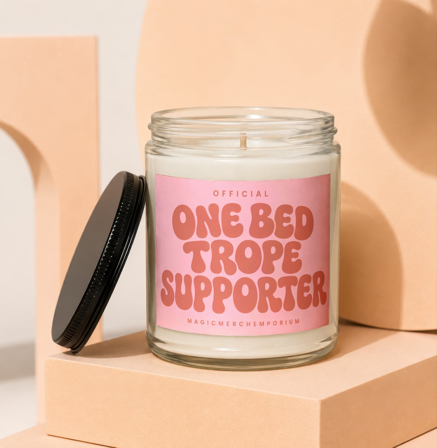 Candle with "Official One Bed Trope Supporter" text on a pink label.